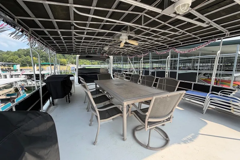 Slide: The Image of Upper deck of a Lakeview houseboat with dining table and chairs, docked at a marina. - 46