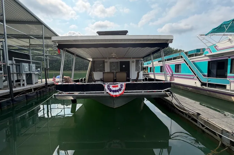 Slide: The Image of Houseboat docked at marina, featuring covered deck and patriotic bunting. - 50