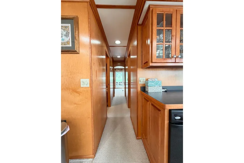 Slide: The Image of Narrow hallway in a Lakeview houseboat with wooden cabinets and carpet flooring. - 17