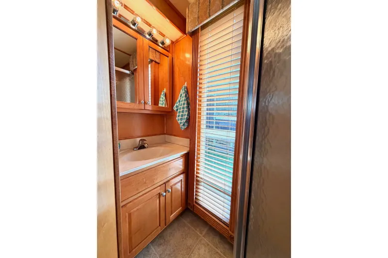 Slide: The Image of Compact bathroom with wooden cabinetry, sink, mirror, and window blinds in a Lakeview model. - 20