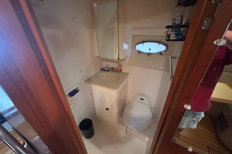 Slide: The Image of Bathroom interior of 2002 Tiara Yachts 3500 Open, featuring sink, toilet, and porthole window. - 29