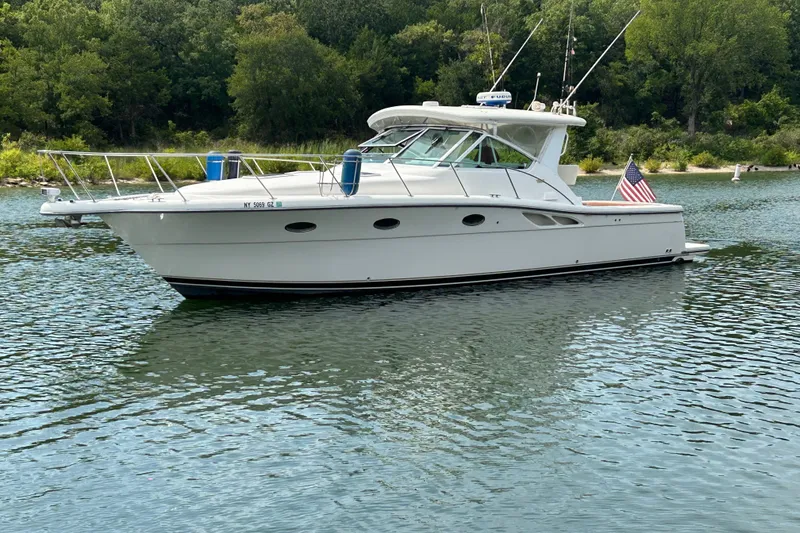 Slide: The Image of 2002 Tiara Yachts 3500 Open cruising on a serene lake with lush greenery. - 3