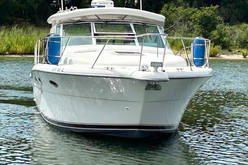 Slide: The Image of 2002 Tiara Yachts 3500 Open cruising on a serene waterway, surrounded by lush greenery. - 5