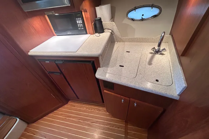 Slide: The Image of 2002 Tiara Yachts 3500 Open galley with sink, microwave, and wooden cabinetry. - 32