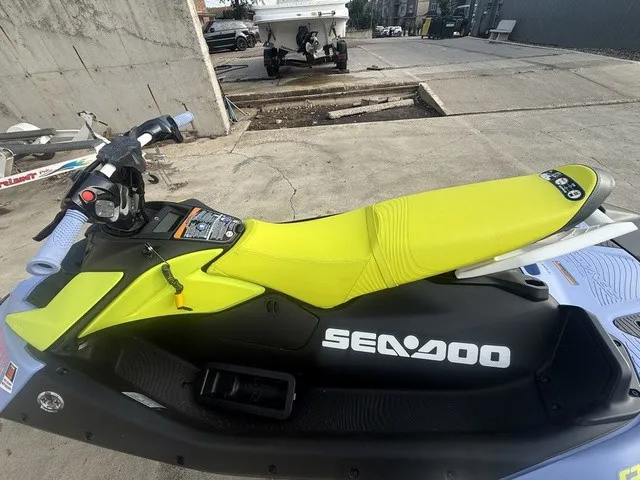 Slide: The Image of A 2024 Sea-Doo Spark Trixx for 3 with a yellow seat and black hull, parked on concrete. - 7