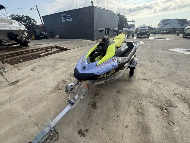 Slide: The Image of A 2024 Sea-Doo Spark Trixx for 3 on a trailer in a marina area. - 2