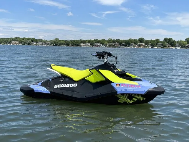 The Image of A 2024 Sea-Doo Spark Trixx for 3 floats on a calm lake with a wooded shoreline. - 1