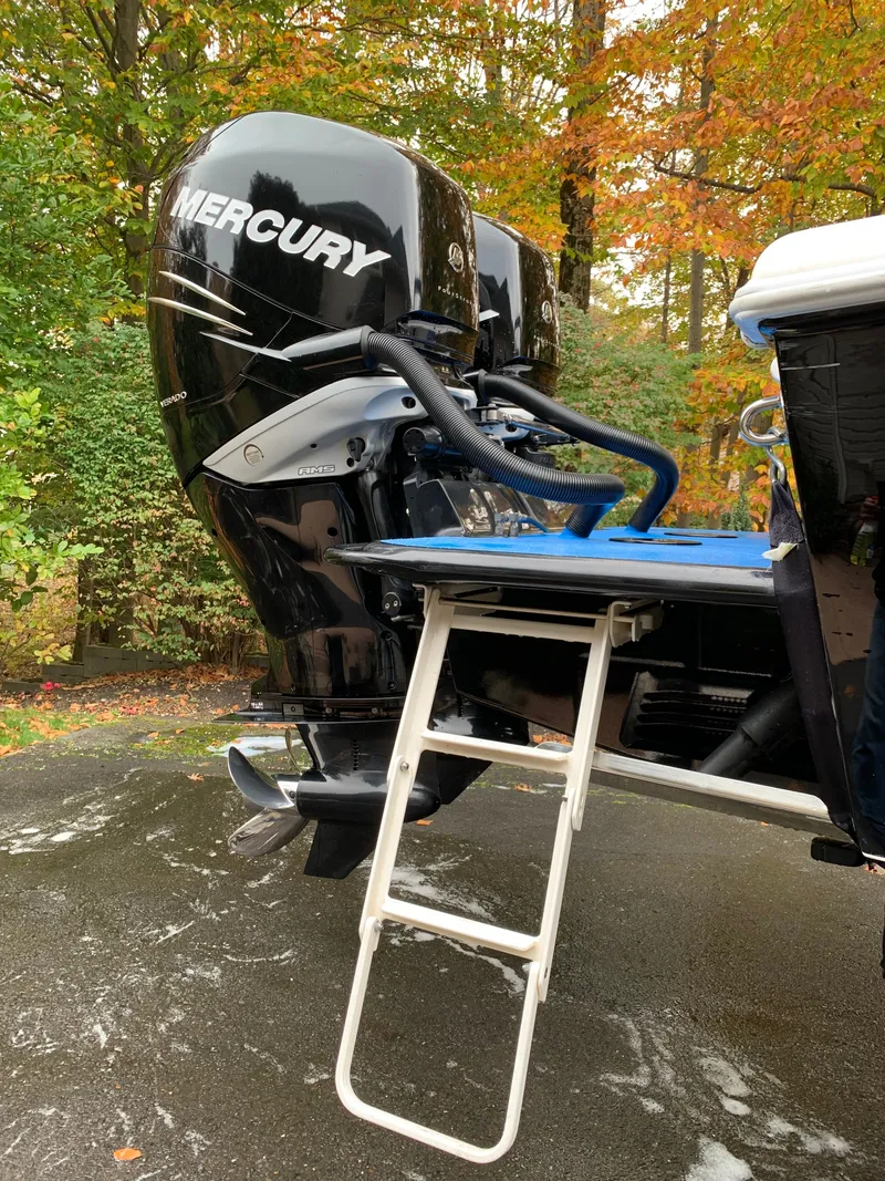 Slide: The Image of A Mercury outboard motor on a boat with a ladder. Autumn foliage in the background. - 20
