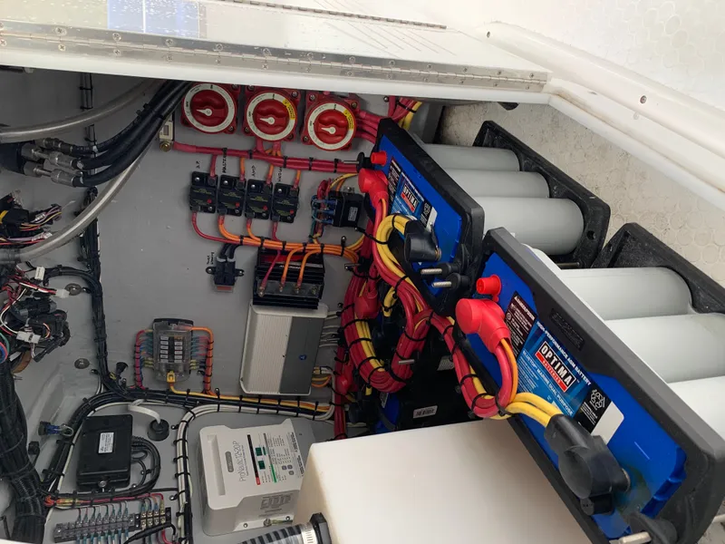 Slide: The Image of The engine compartment of a boat shows batteries, wiring, and electrical components in a compact space. - 18