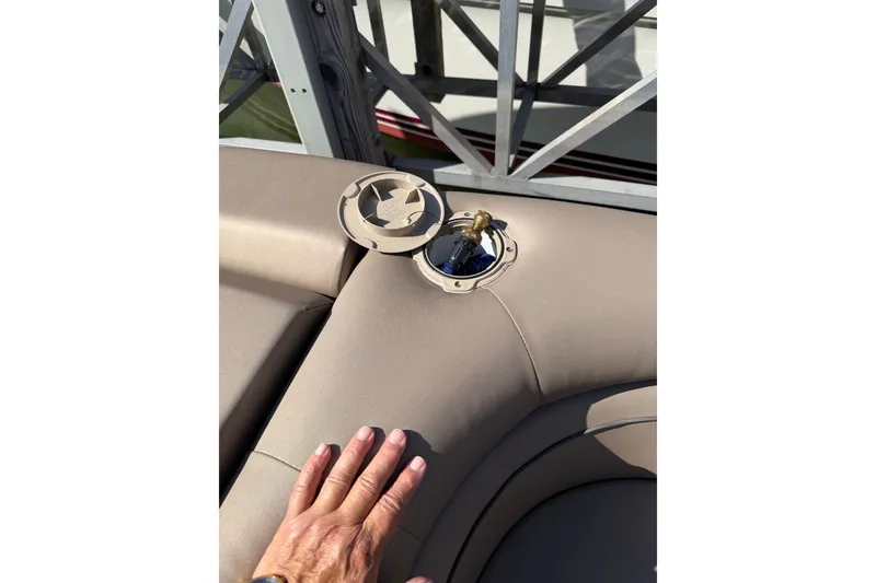Slide: The Image of 2022 Bennington L 25 FISHING SSAPG boat seat with open fuel cap and hand. - 16