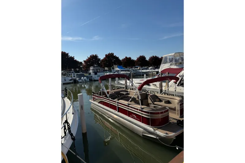 Slide: The Image of 2022 Bennington L 25 FISHING SSAPG pontoon boat docked in marina under clear sky. - 2