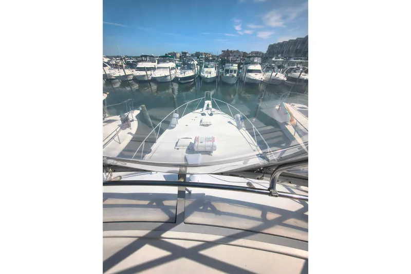Slide: The Image of 1985 Bertram 42 Convertible yacht docked in a marina under a clear blue sky. - 23