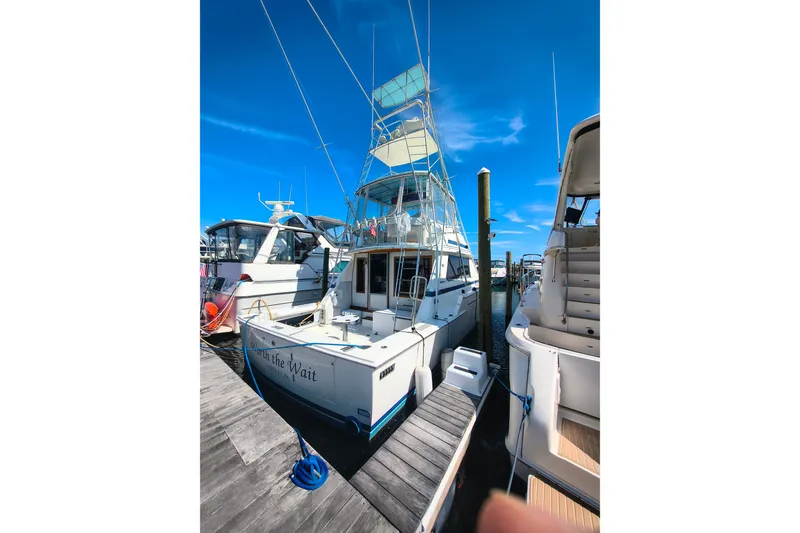 Slide: The Image of 1985 Bertram 42 Convertible yacht docked at marina under clear blue sky. - 22