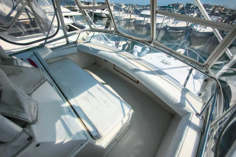 Slide: The Image of 1985 Bertram 42 Convertible yacht interior with white seating and marina view. - 9