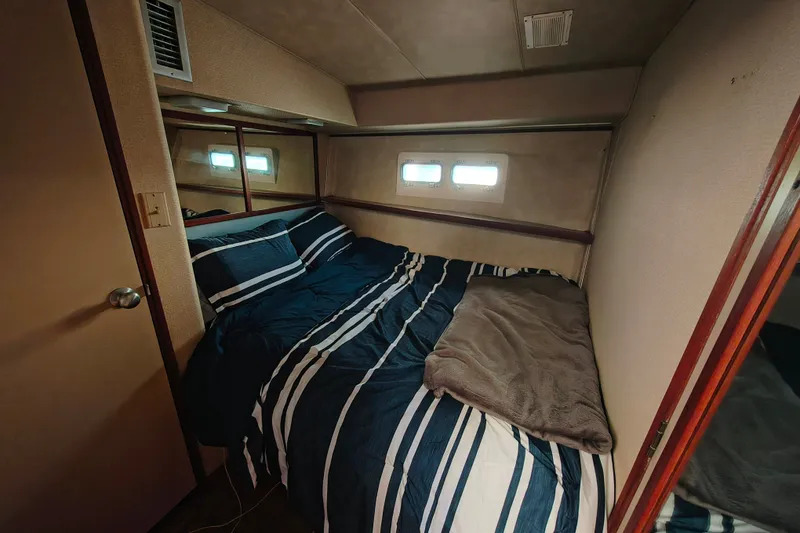 Slide: The Image of Cozy bedroom interior of 1985 Bertram 42 Convertible yacht with striped bedding. - 20