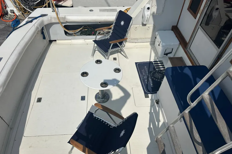 Slide: The Image of 1985 Bertram 42 Convertible yacht deck with chairs, table, and nautical decor. - 2
