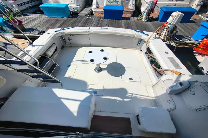 Slide: The Image of Cockpit of 1985 Bertram 42 Convertible yacht with seating and table, docked at marina. - 4