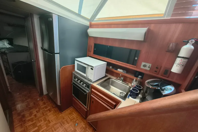Slide: The Image of Compact kitchen in a 1985 Bertram 42 Convertible yacht with microwave, sink, and refrigerator. - 17