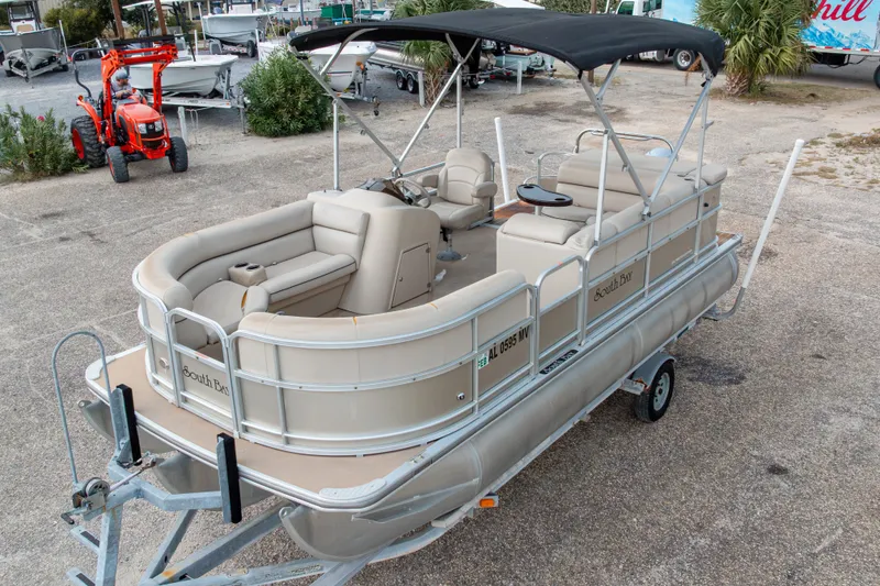 Slide: The Image of 2016 South Bay 5220CR pontoon boat with canopy on a trailer in a parking lot. - 2