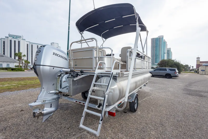 Slide: The Image of 2016 South Bay 5220CR pontoon boat with Honda outboard motor, parked near buildings. - 37