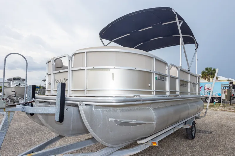 Slide: The Image of 2016 South Bay 5220CR pontoon boat on trailer with canopy, parked outdoors. - 12