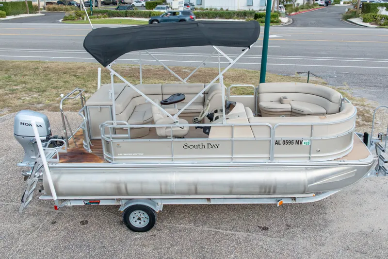 Slide: The Image of 2016 South Bay 5220CR pontoon boat with Honda motor on trailer, parked near road. - 4