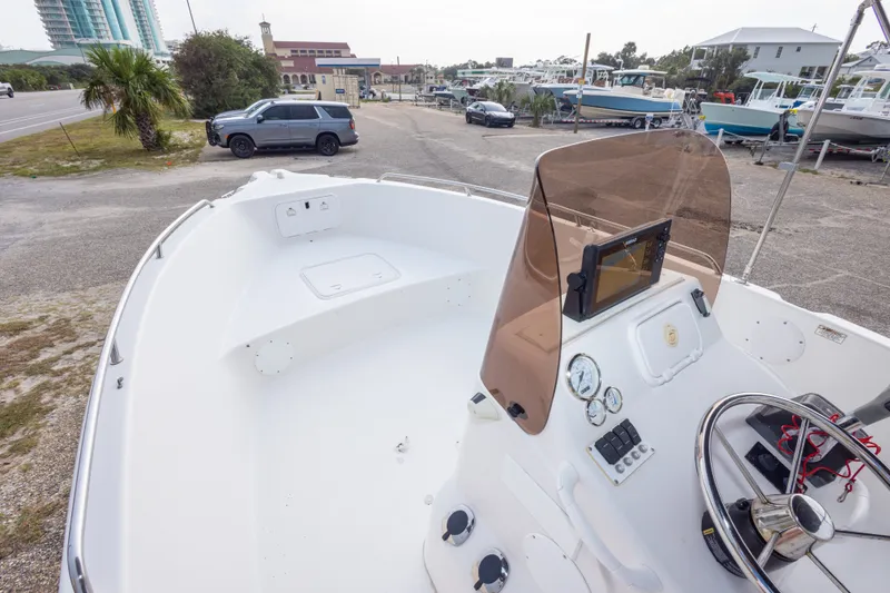 Slide: The Image of 2011 PROLINE 21 CC SE boat with console and steering wheel, parked near other boats. - 30
