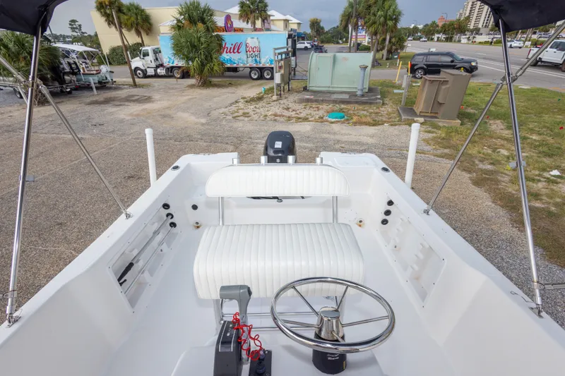 Slide: The Image of 2011 PROLINE 21 CC SE boat interior with steering wheel and seating, parked outdoors. - 21