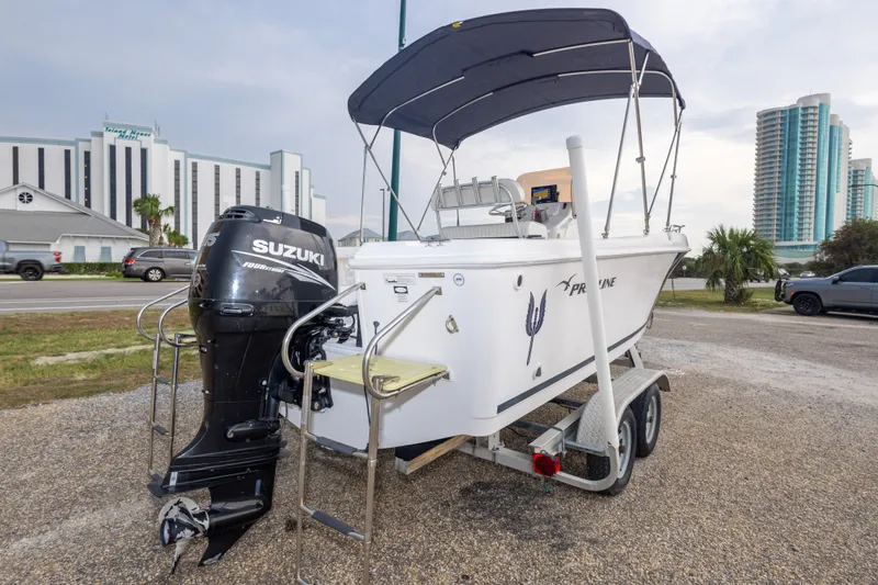 Slide: The Image of 2011 PROLINE 21 CC SE boat with Suzuki outboard motor on trailer, parked near buildings. - 42