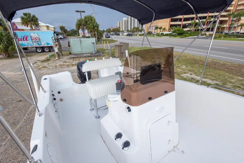 Slide: The Image of 2011 PROLINE 21 CC SE boat interior with seating and console, parked near a road. - 23
