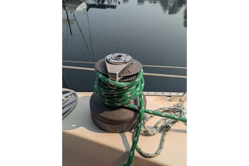 Slide: The Image of Winch with green rope on 1988 Ericson 38-200 sailboat deck, docked by calm water. - 31