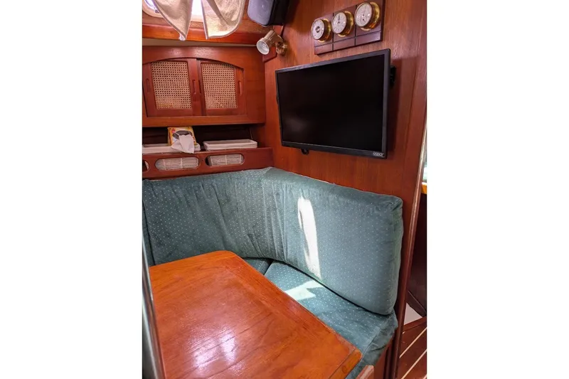 Slide: The Image of Interior of 1988 Ericson 38-200 sailboat with cozy seating, wooden table, and mounted TV. - 41
