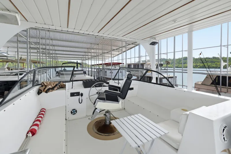 Slide: The Image of Helm of 2002 Monticello 16x70 houseboat in marina, featuring captain's chair and controls. - 17