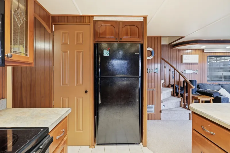 Slide: The Image of Kitchen interior of 2002 Monticello 16x70 houseboat with wood paneling and black refrigerator. - 49