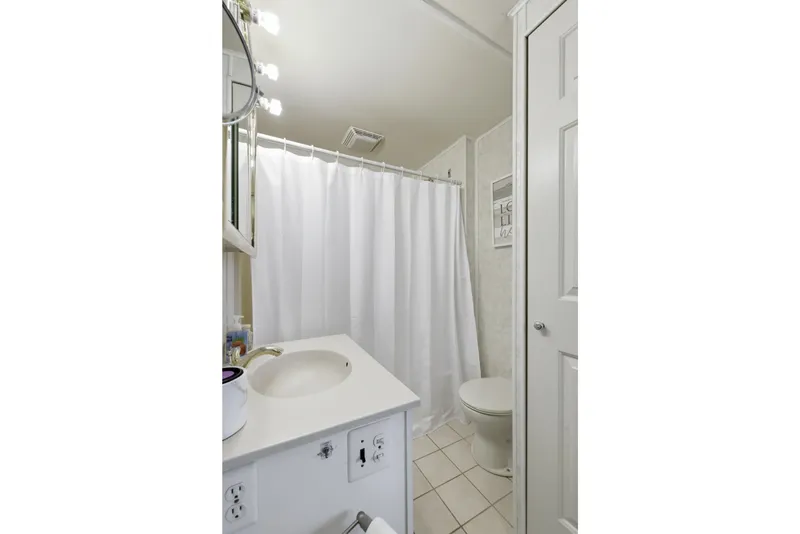 Slide: The Image of Compact bathroom with white fixtures, shower curtain, and bright lighting in a 2002 Monticello 16x70. - 61