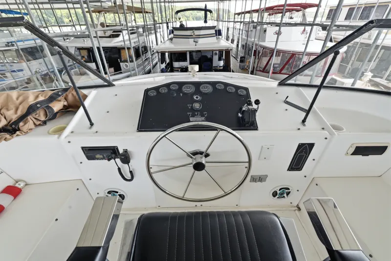 Slide: The Image of Steering console of a 2002 Monticello 16x70 houseboat in a marina. - 18