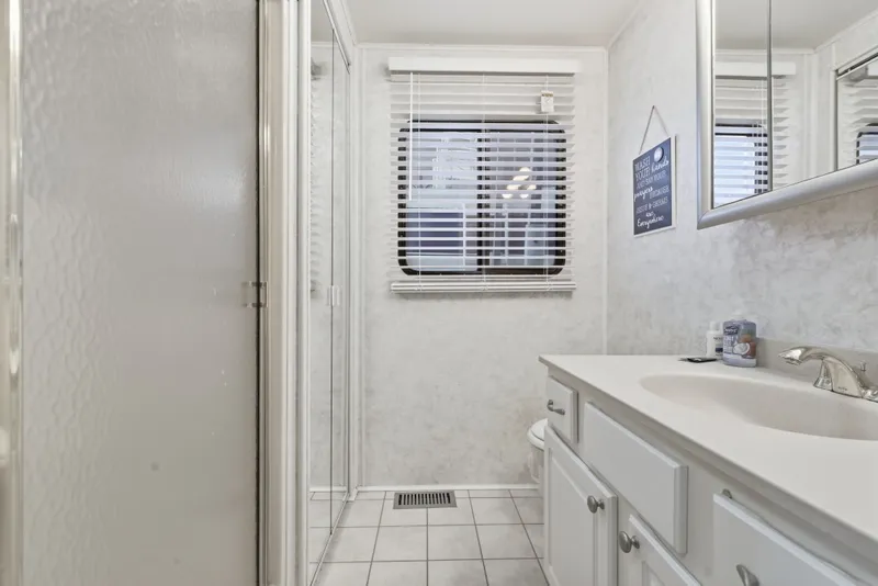 Slide: The Image of Compact bathroom with white cabinetry, tiled floor, and a window with blinds in a 2002 Monticello 16x70. - 44