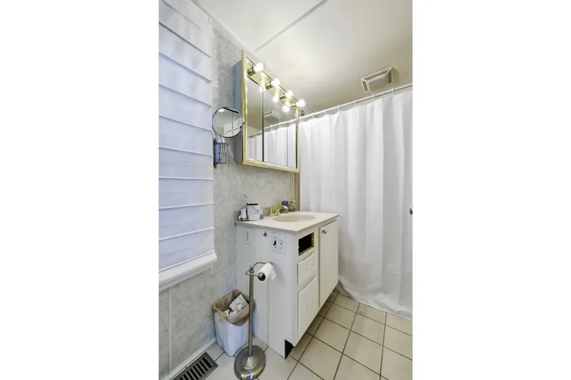 Slide: The Image of Small bathroom with white vanity, mirror, and shower curtain in a 2002 Monticello 16x70 model. - 60