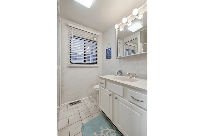 Slide: The Image of Small bathroom with white cabinets, mirror, and window blinds in a Monticello 16x70, 2002 model. - 43