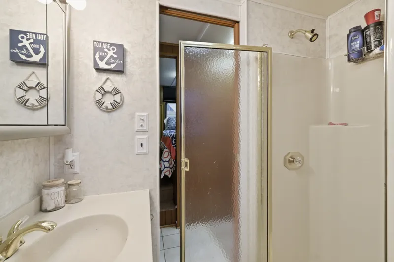 Slide: The Image of Bathroom in 2002 Monticello 16x70 model with shower, nautical decor, and vanity. - 46
