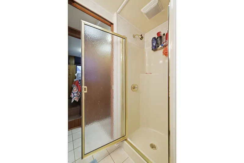 Slide: The Image of Shower area in a 2002 Monticello 16x70, featuring glass door and toiletries. - 47