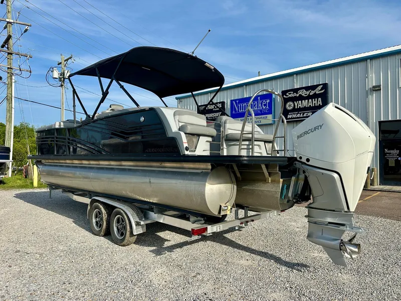 Slide: The Image of 2021 Harris Grand Mariner 250 pontoon boat on trailer, parked outside dealership. - 2