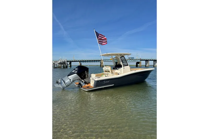 The Image of 2020 Scout 235 XSF boat with American flag, docked in calm waters under clear blue sky. - 0