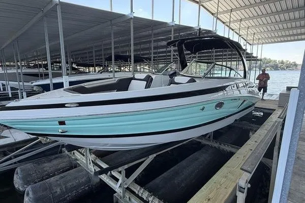 The Image of 2024 Crownline 290 SS boat docked under a covered marina, featuring sleek design and turquoise accents. - 0