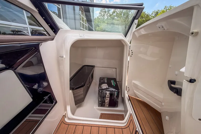 Slide: The Image of 2023 Yamaha Boats 275SE storage compartment with wooden flooring and open door. - 20