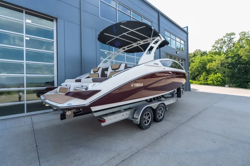 Slide: The Image of 2023 Yamaha Boats 275SE on trailer, parked outside modern building. - 2