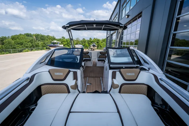 Slide: The Image of 2023 Yamaha Boats 275SE with luxurious seating and sleek design, docked outdoors. - 24