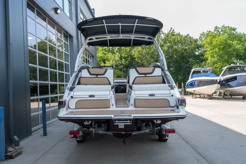 Slide: The Image of 2023 Yamaha Boats 275SE, rear view, parked outdoors near other boats. - 3
