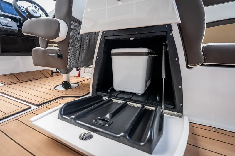 Slide: The Image of 2023 Yamaha Boats 275SE interior with storage compartment and cooler on teak flooring. - 28