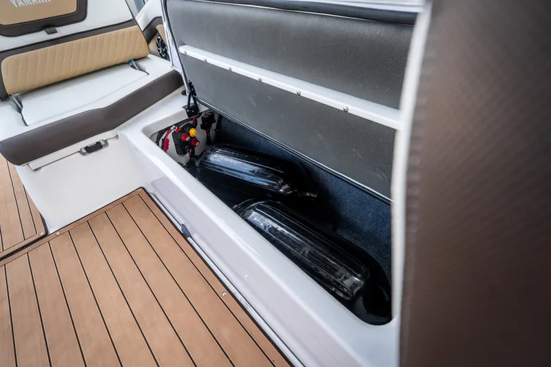 Slide: The Image of 2023 Yamaha Boats 275SE storage compartment with fenders and teak flooring. - 32